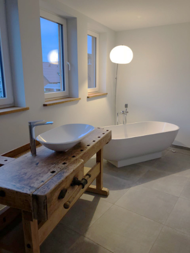 gefliestes Badezimmer mit Waschtisch aus Holz und Badewanne